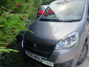 front of wheelchair accessible taxi next to bush